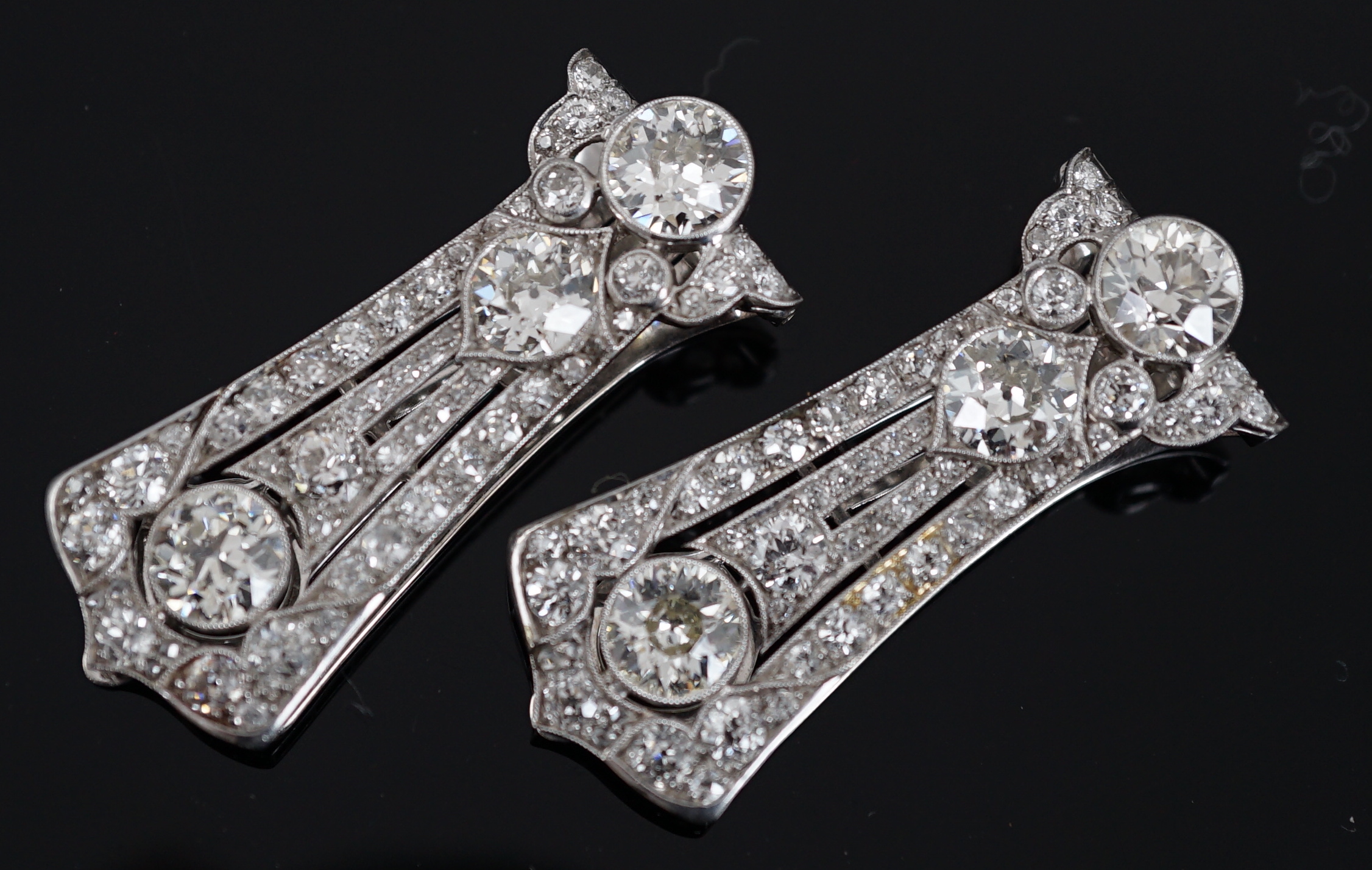A pair of Art Deco white gold and round cut millegrain set diamond cluster clip brooches